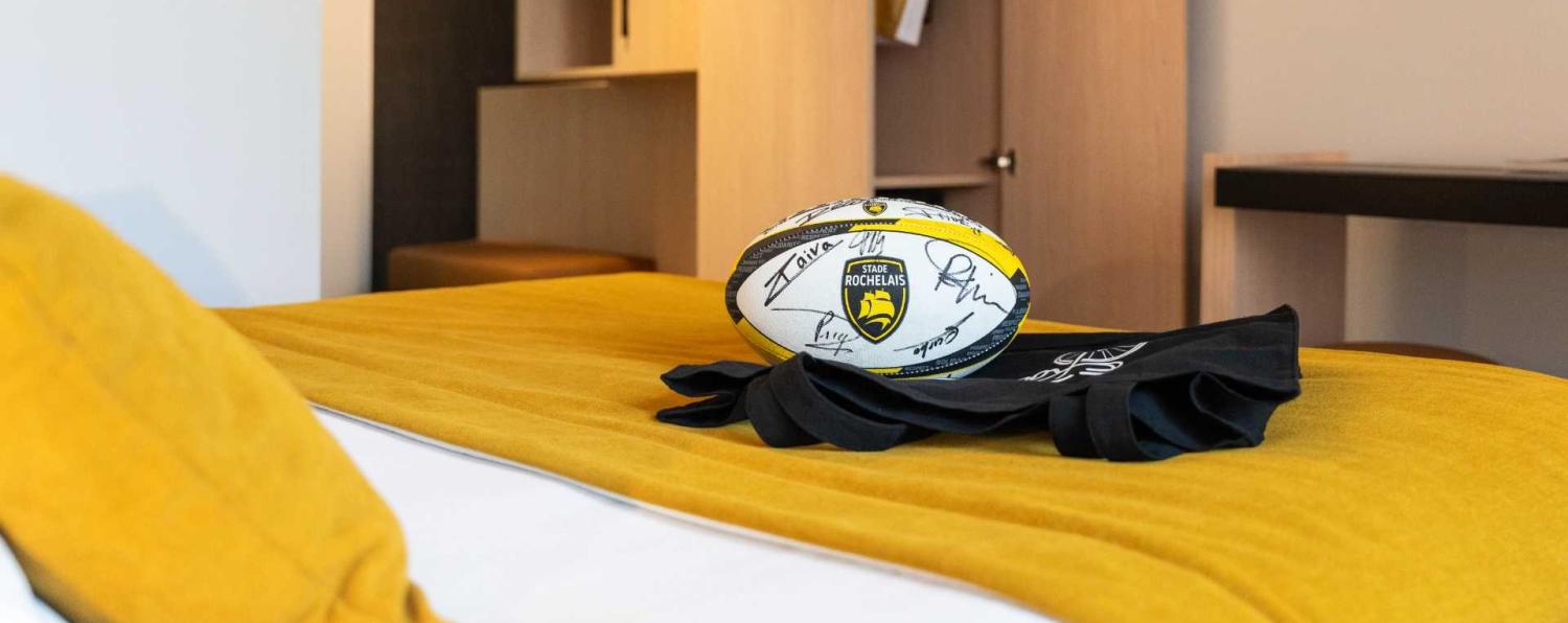 ballon de rugby du stade rochelais posé sur un lit d'hôtel à la rochelle